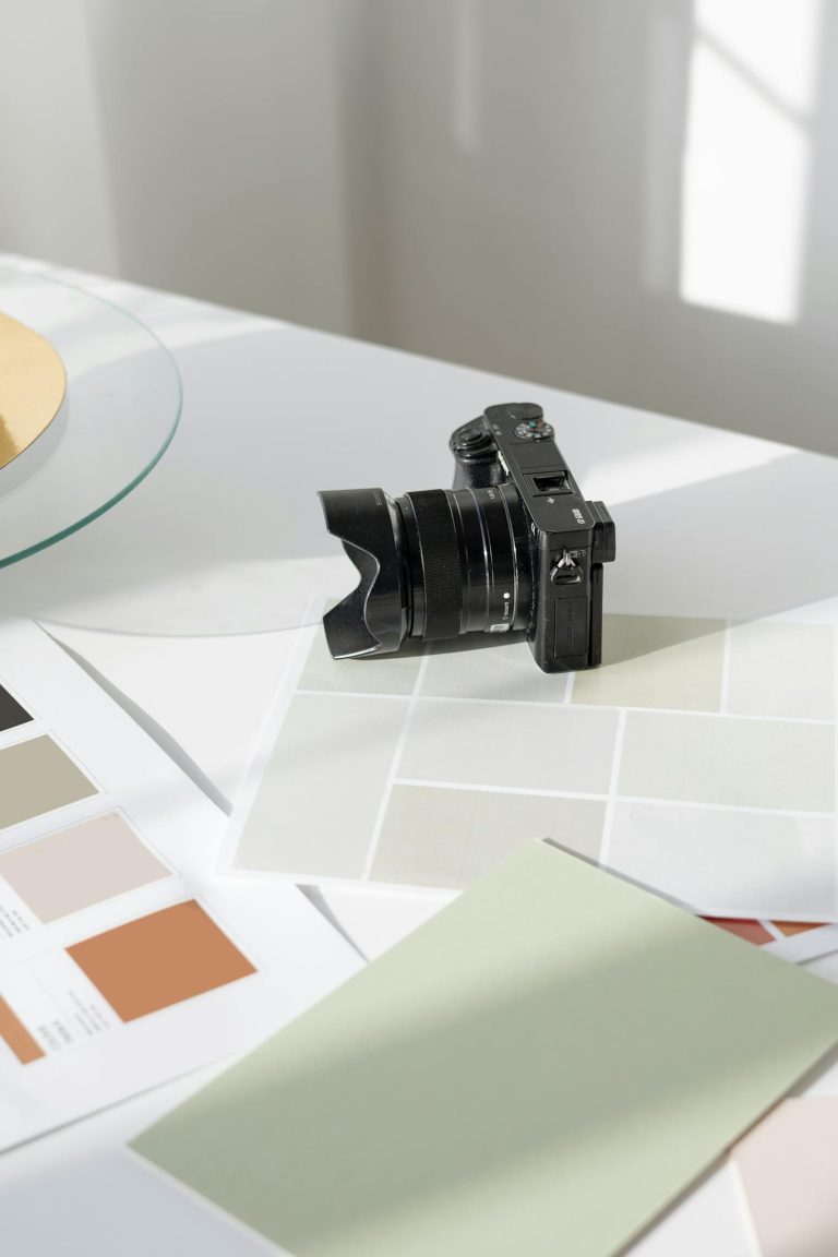 Digital camera resting on a desk with color swatches and design materials.
